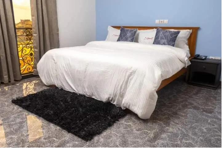 Chambre meublée avec grand lit et porte-fenêtre sur balcon en fer forgé