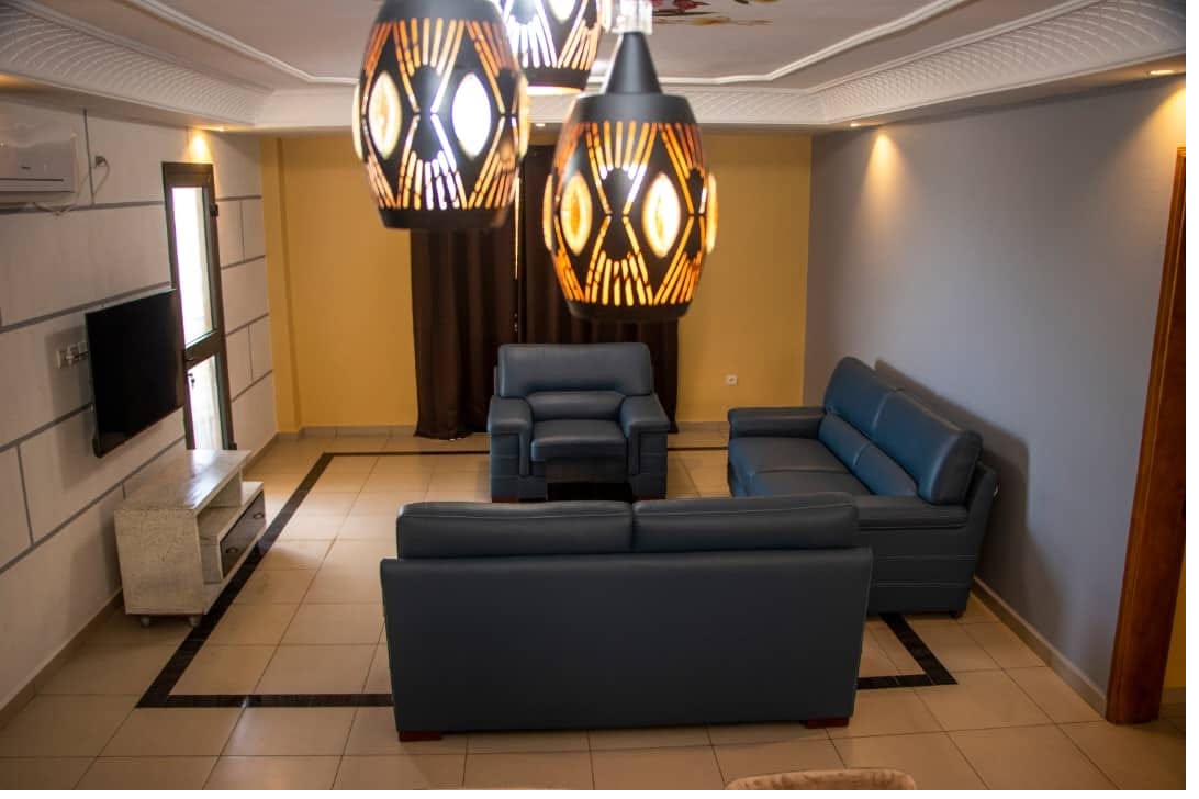 Grand salon en cuir bleu avec luminaires en vannerie et téléviseur mural