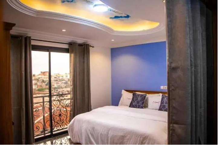 Chambre de la suite junior, mur bleu et balcon donnant sur la ville